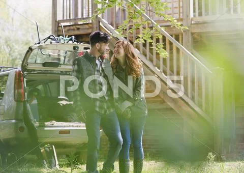 Couple holding hands outside car and cabin Stock Photos