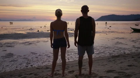 Couple holding hands at sunset on beach Stock Footage 74778779