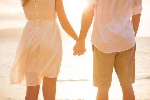 Couple holding hands at sunset on beach. romantic young couple in love Stock Photos