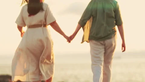 Couple holding hands walking on beach at sunset Stock Footage 313277757
