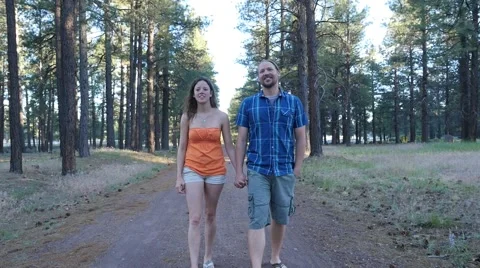 A couple holding hands walking down a trail Stock Footage 64385770
