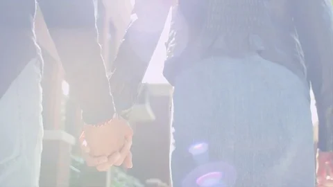 A couple holding hands walking down the sidewalk, close up, lens flare Stock Footage