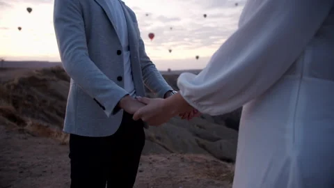 Couple holding hands while hot air ballons fly at sunrise 動画素材 141901385