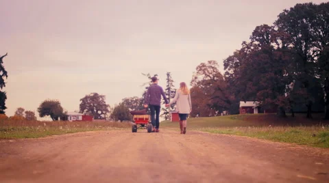 A couple holding hands while pulling a wagon at a pumpkin patch Stock Footage 58596077