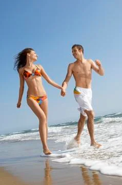 Couple Holding Hands While Running In Surf At Beach Stock Photos