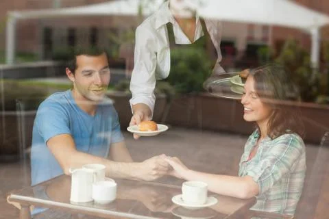 A couple holding hands while waitress serving food Fotos Stock