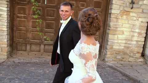Couple holding hands while walking in the park near the old castle. Slow motion Stock Footage 82832938