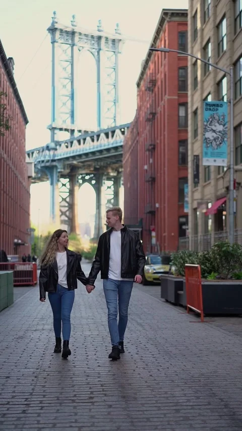 Couple is holding hands while walking under a beautiful bridge in New York City 스톡 동영상 291622953