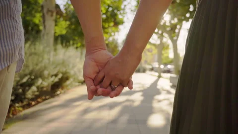 Couple holding hands while walking in a park Stock Footage 303854532