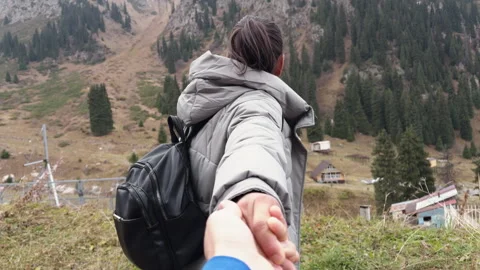 Couple holding hands while walking towards mountain scenery Stock Footage 318359860