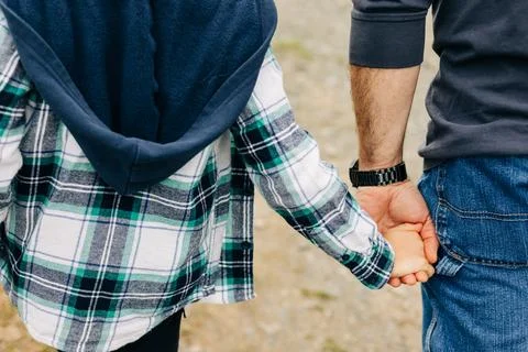 Couple holding hands while walking on a gravel path in a serene outdoor setting Stock Photos