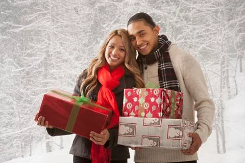 Couple holding presents in snow Stock Photos