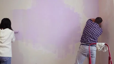 Couple holding roller bush apply violet color paint new home apartment Vídeo Stock 257965111