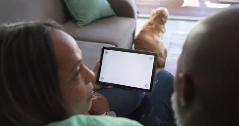 Couple holding tablet on couch, leaning in and inspecting blank screen corner Stock Footage 342493187