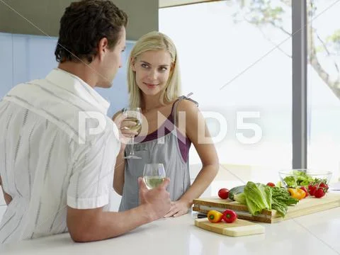 Couple Holding Wineglasses At Kitchen Counter Stock Photos