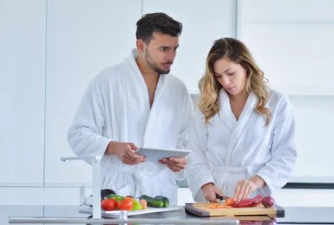 Couple in home kitchen using electronic tablet Фото