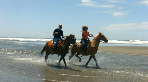 Couple horseback riding on beach, slow motion Stock Footage