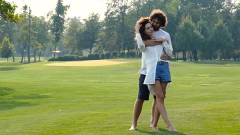 Couple hugging, talking, standing on the green grass outdoors. Slow motion. Stock Footage 94563771