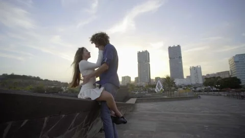 The couple hugs against the backdrop of the city and the sunset. A girl and a gu Stock Footage 221273053