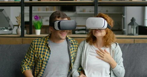 Couple is impressed with virtual reality video, sitting on sofa, close up Stock Footage 114893852