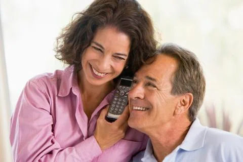 Couple indoors using telephone smiling Stock Photos