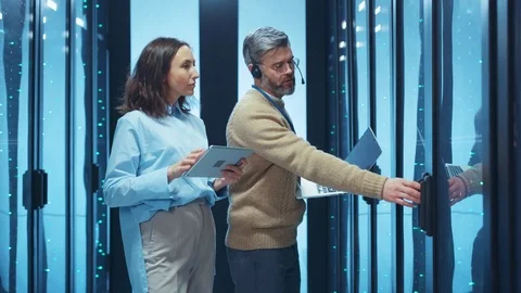 Couple of IT server technicians setting up and activating server cabinet in data Stock Footage 124550360