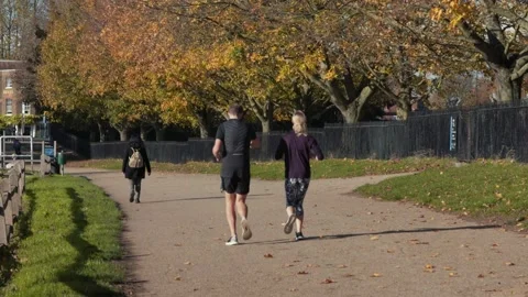 A couple jogging past the camera on the Thames path, UK Stock Footage 145831184