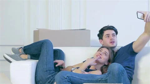 A couple joyfully capturing a selfie while surrounded by moving boxes Stock Footage 311535568