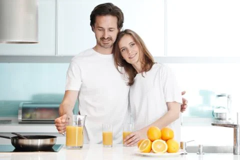 Couple with juice in the kitchen Stock Photos