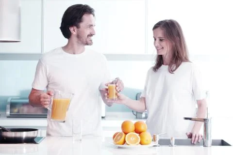 Couple with juice in the kitchen Stock Photos
