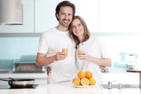 Couple with juice in the kitchen Stock Photos
