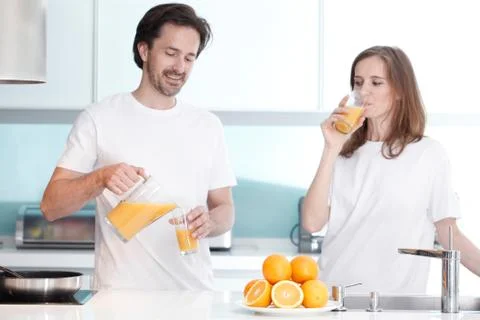 Couple with juice in the kitchen Stock Photos