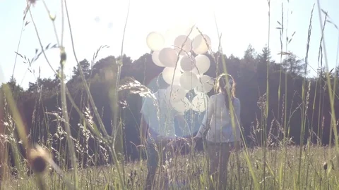Couple jumping in the field with balloons Stock Footage 76874287