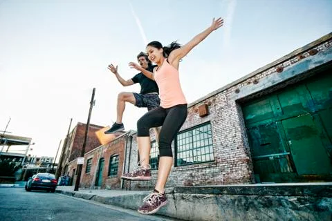 Couple jumping off loading dock Stock Photos