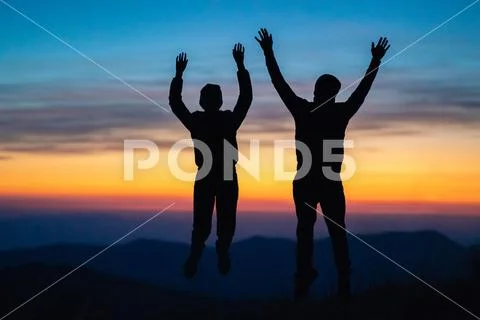 The couple jumping on the mountain on the sunset background Stock Photos