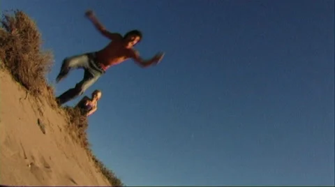 Couple jumping in sand dune on beach Stock Footage 43688638