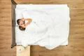 The couple kiss on the bed with white linens. View from above Photo