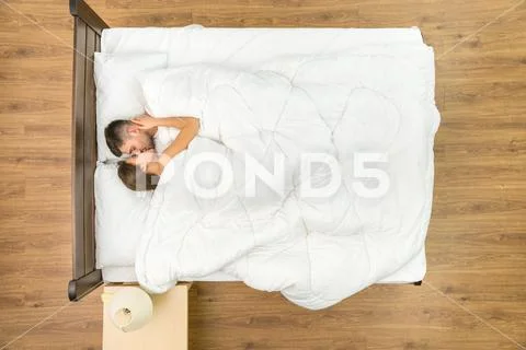 The couple kiss on the bed with white linens. View from above Stock Photos