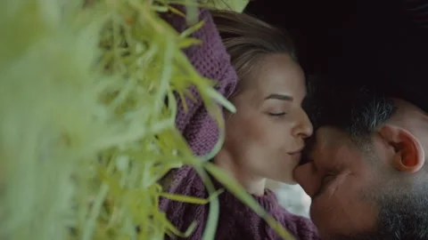 Couple kissing one another while lying down outdoors on grass Stock Footage 275275327