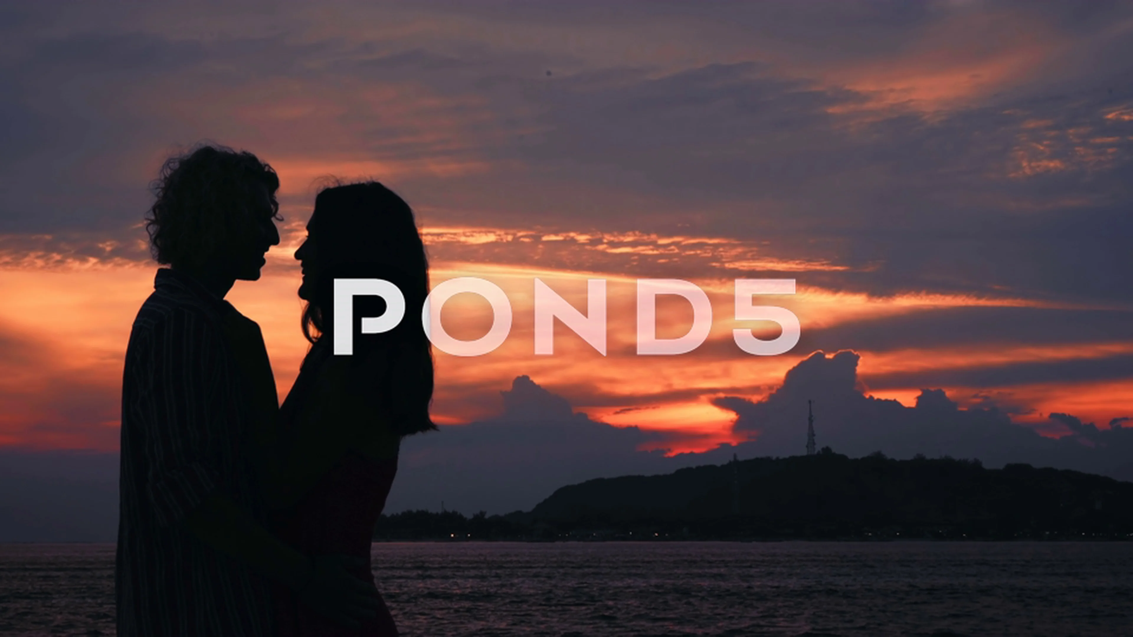 Couple kissing silhouettes in front of ocean sunset