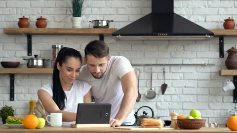 Couple at the kitchen. Looking at the difital tablet together. Web searching. Video stock 105410869