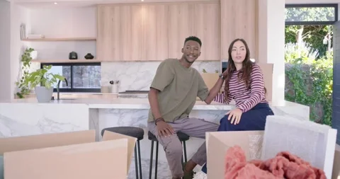 Couple laughing, gesturing, and holding hands after moving in at marble kitchen Stock Footage 337730101