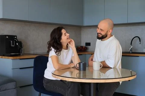 Couple laughing together while drinking coffee in a modern kitchen Foto stock