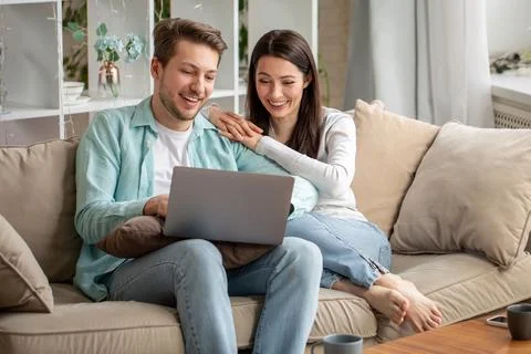 Couple laughing while browsing laptop together Stock Photos