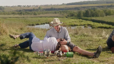 Couple laughing while resting by river and preparing hot drinks Stock Footage 247029559