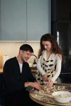 Couple Laughing While Shaping Dumplings at Kitchen Table Foto stock
