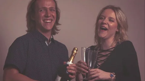 Couple Laughs While Holding Champagne and Glasses in Slow Motion Stock Footage 72127250