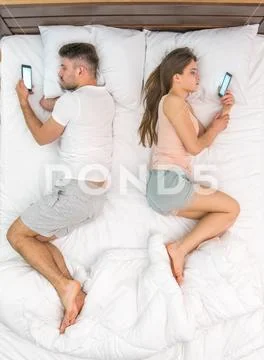 The couple lay on the bed and phone. View from above Stock Photos