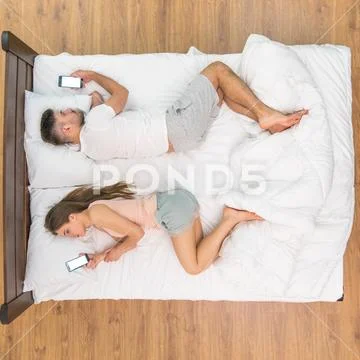 The couple lay on the bed and phone. View from above Stock Photos