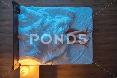 The couple lay under blanket on the bed. evening night time. view from above Stock Photos